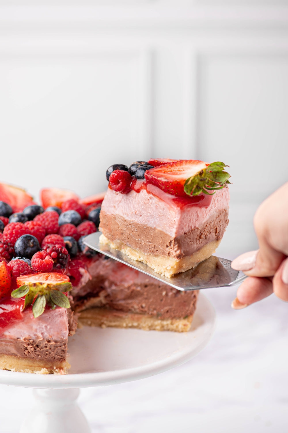 Un trozo de cheesecake de berries y chocolate siendo cortado.