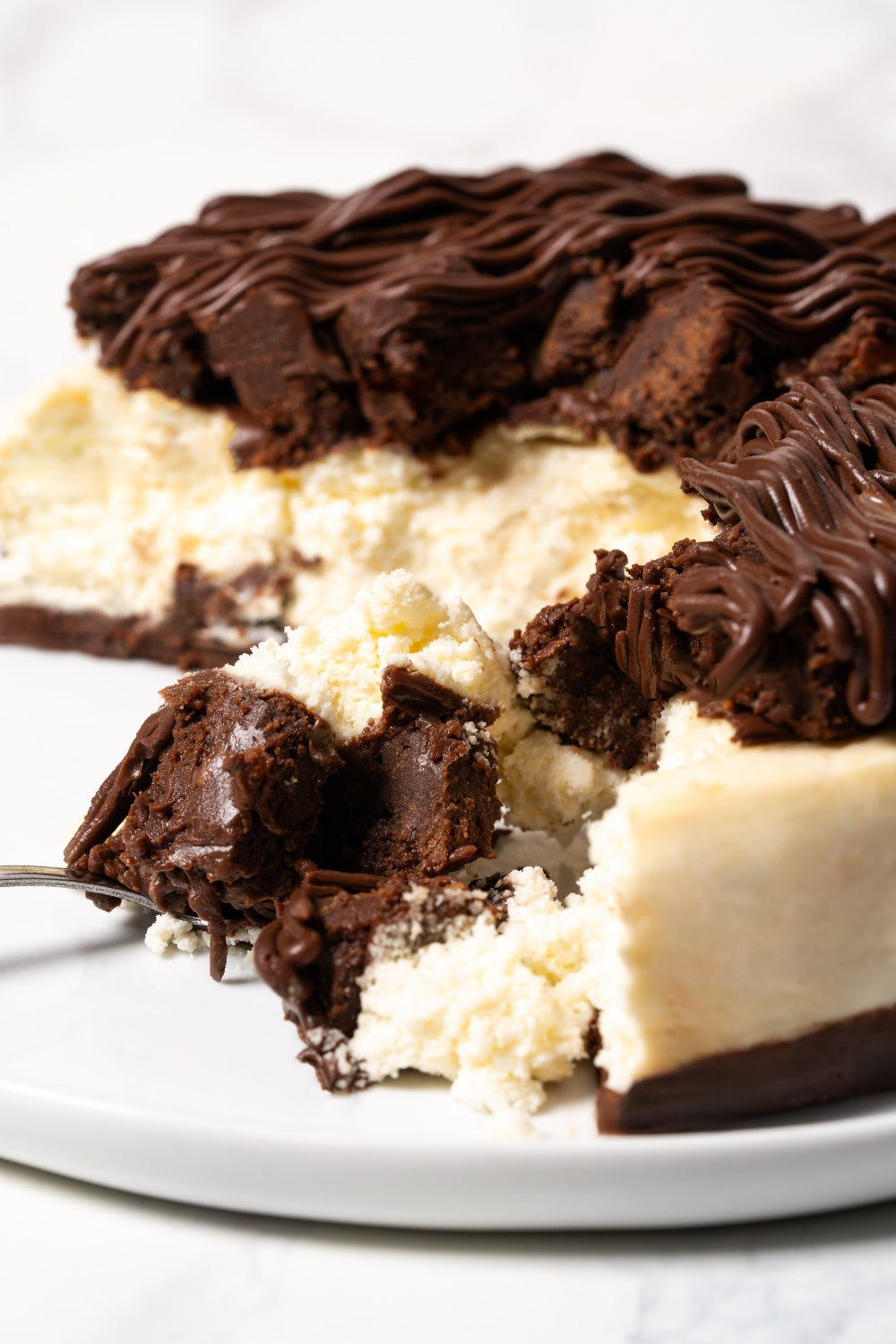 Un trozo de cheesecake de brownie sobre un plato.