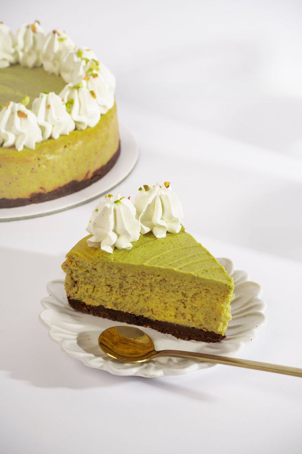 Un trozo de un cheesecake de pistachos sobre un plato. 