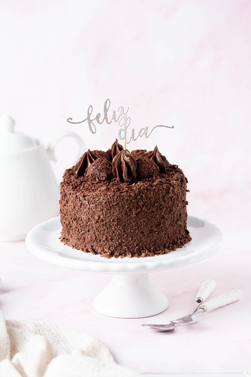 Mini torta de chocolate sobre un parante con un topper encima que dice "feliz día". 