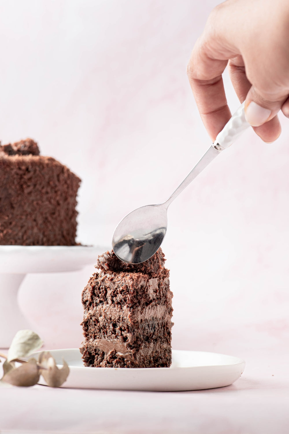 Pedazo de una mini torta de chocolate. Una mano se acerca con una cuchara al postre.  