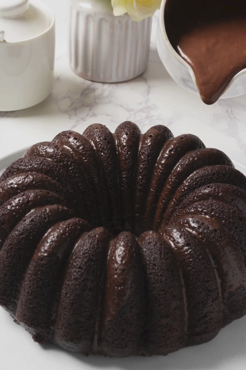 Proceso en el que se vierte salsa de chocolate sobre un bundt cake de chocolate. 